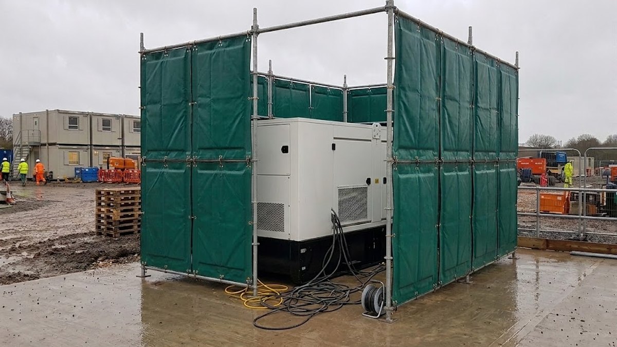 Scaffold-mounted acoustic barrier panels enclosing a diesel generator on a wet UK construction site